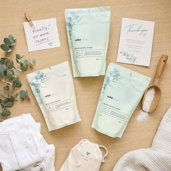 Wild & Free Home Natural Laundry Powder flatlay with baby clothes and a thank you note